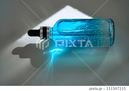 A blue bottle of hyaluronic serum for the face in the bright sun. A blue bottle of hyaluronic serum for the face in the bright sun. 131307135