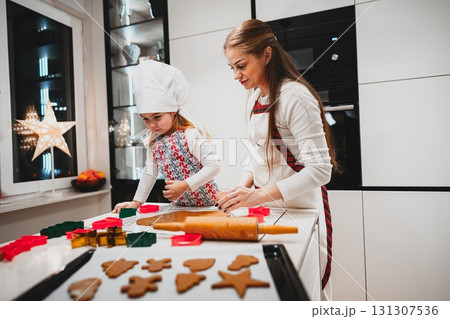 A heartwarming scene of a cheerful mother and her daughter joyfully baking festive cookies together in the kitchen A heartwarming scene of a cheerful mother and her daughter joyfully baking festive cookies together in the kitchen 131307536
