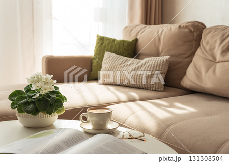 Cozy Living Room with Coffee, Book and African Violet on Table Cozy Living Room with Coffee, Book and African Violet on Table 131308504