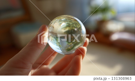 Hand holding a clear crystal lens ball reflecting the outdoors Hand holding a clear crystal lens ball reflecting the outdoors 131308963
