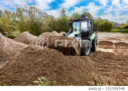 Excavator loader used for distributing and leveling sand on site. 131309346