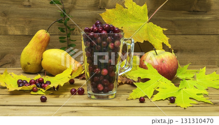 Autumn Still Life. Cranberries in a glass with autumn leaves, apples and pears. 131310470