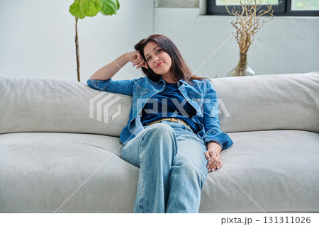 Portrait of relaxed beautiful smiling brunette woman sitting on sofa in living room 131311026