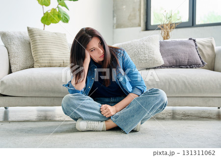 Sad upset young woman with sitting on floor near sofa at home Sad upset young woman with sitting on floor near sofa at home 131311062