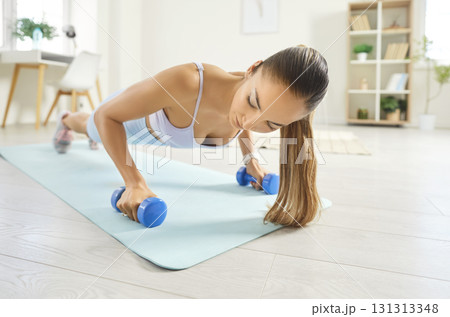 Woman Doing Pushups With Dumbbells In Plank Position During Home Workout Woman Doing Pushups With Dumbbells In Plank Position During Home Workout 131313348