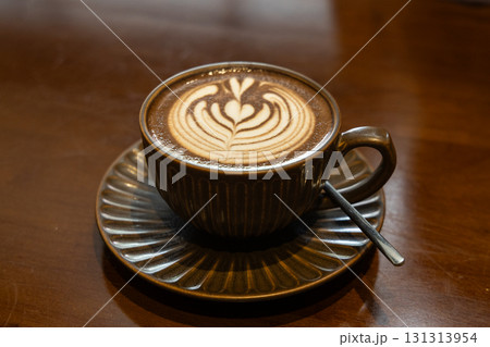 Cuppa of aromatic hot cafe mocha with lovely heart shaped art served in brown cup and saucer on brown table top 131313954