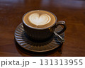 Cuppa of aromatic hot cafe latte with lovely heart shaped art served in brown cup and saucer on brown table top 131313955