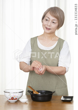 キッチンでおにぎりを握るシニア女性 131314633