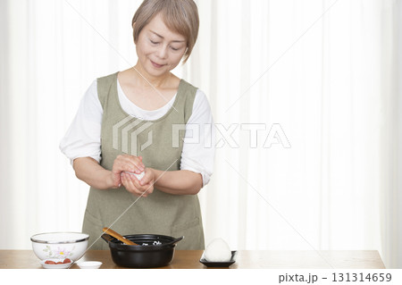 キッチンでおにぎりを握るシニア女性 131314659