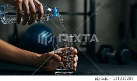 A person pours water into a glass, promoting hydration and self-care during National Wellness Month 131316289
