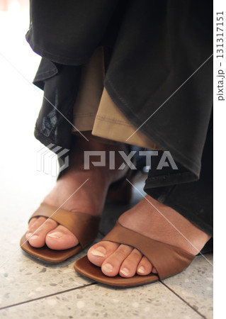 Stylish brown sandals on a tiled floor near a casual setting 131317151