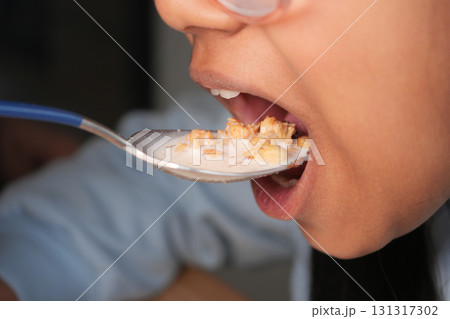 Child enjoys cereal with milk during breakfast time 131317302