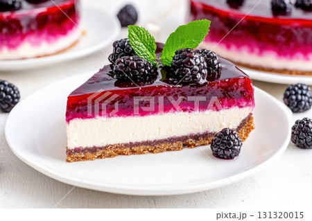 Delicate blackberry cheesecake with layers of creamy filling and a vibrant plum-colored glaze is served on a white plate, garnished with fresh blackberries and mint. 131320015