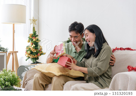 Christmas love, happy couple enjoys cozy winter holiday, opening gifts with cheer, warm home celebration creates memorable christmas happiness, spreading pure joy. 131320193