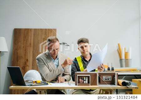 Architects and engineers collaborating on blueprints and models, showcasing teamwork, planning 131321484