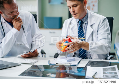 Doctors analyzing an X-ray, collaborating with digital tools in a medical office. Showcasing teamwork, diagnostic 131321496