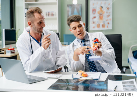 Doctors analyzing an X-ray, collaborating with digital tools in a medical office. Showcasing teamwork, diagnostic 131321497