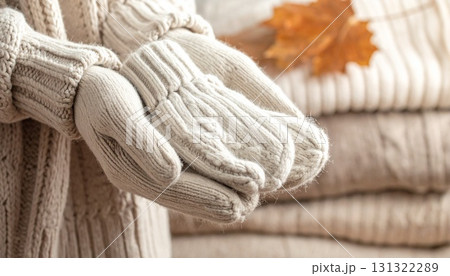 手でウール手袋を持つクローズアップ、背景にレイヤードセーター 131322289