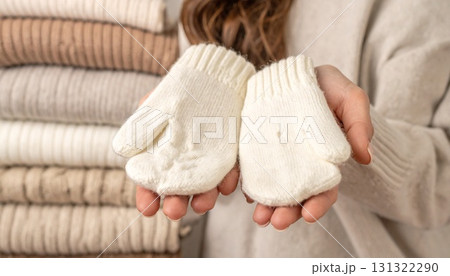 手でウール手袋を持つクローズアップ、背景にレイヤードセーター 131322290