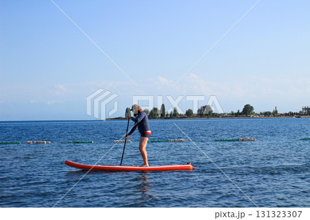 Person paddleboarding on calm water 131323307