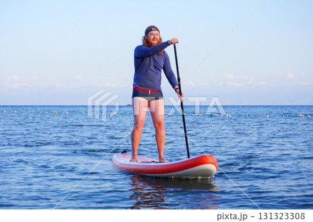 Person paddleboarding on calm sea 131323308