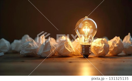 Crumpled paper surrounds a light bulb, illustrating the process of brainstorming and success in educational environments 131325135