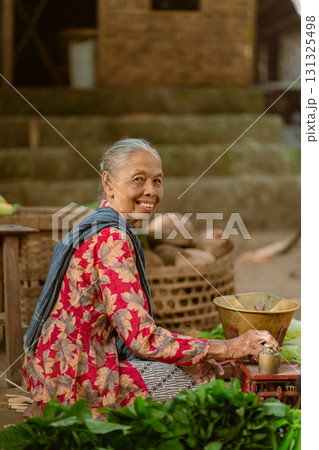 An Elderly Woman Engaged in Preparing Local Ingredients Within a Charming Traditional Setting 131325498