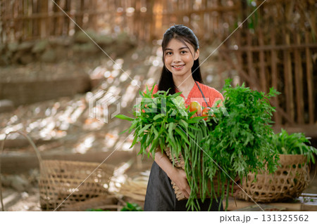 A Young Woman is Actively Harvesting Fresh Vegetables in a Picturesque Rural Setting A Young Woman is Actively Harvesting Fresh Vegetables in a Picturesque Rural Setting 131325562