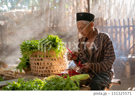 An Elderly Man Intently Preparing Fresh Vegetables in a Serene and Peaceful Environment 131325571