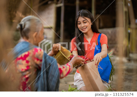 A Young Woman Helping an Elderly Woman in a Community Exchange of support and care 131325574