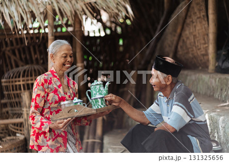 Joyful Elders Enthusiastically Sharing Traditional Sweet Treats in a Rustic Setting 131325656