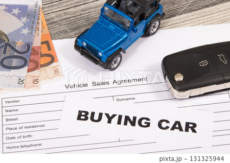 Blue toy car, key, euro banknotes and vehicle sales agreement. Inscription buying car 131325944