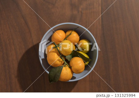 Fresh tangerines in a blue bowl on wood table 131325994