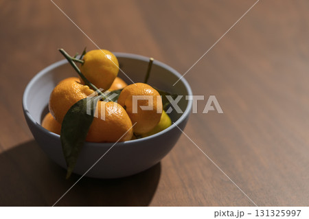 Fresh tangerines in a blue bowl on wood table 131325997