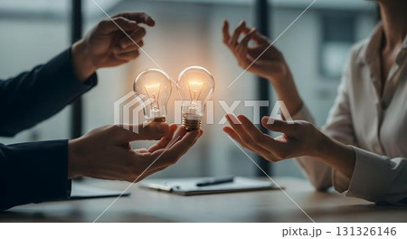 Two professionals holding light bulbs in an office, signifying success and the power of brainstorming together 131326146