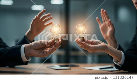Two business people in an office setting, each holding a light bulb, illustrating achievement and collaborative thinking 131326147