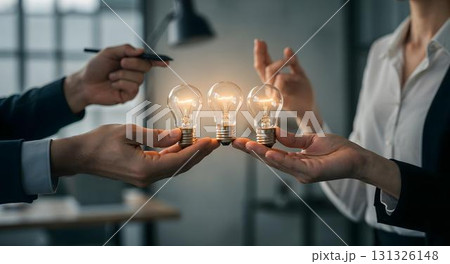 Two colleagues in a meeting room proudly displaying light bulbs, representing brainstorming and successful teamwork 131326148