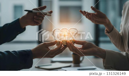 Two business professionals in an office holding light bulbs, symbolizing collaboration and innovative ideas 131326149