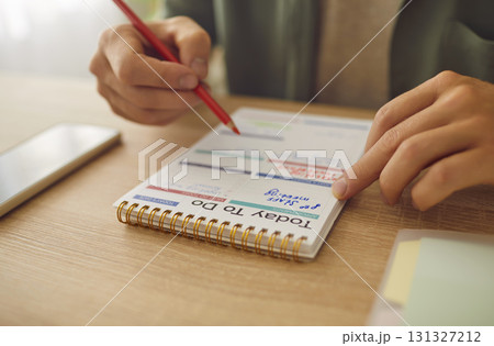 Business man hands writing plan to do list in his planner notepad sitting at table. Business man hands writing plan to do list in his planner notepad sitting at table. 131327212