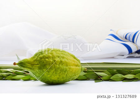 Sukkot Symbols. Yellow etrog with lulav branches on a Jewish prayer shawl symbolizing the Sukkot festival 131327689