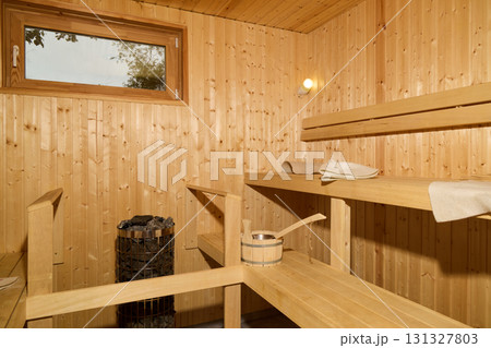 Enjoy a cozy wooden sauna with inviting benches and relaxing accessories for your pleasure 131327803