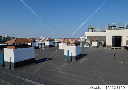 A vibrant Urban Rooftop showcases Ventilation Structures against a backdrop of a Clear Blue Sky A vibrant Urban Rooftop showcases Ventilation Structures against a backdrop of a Clear Blue Sky 131328130