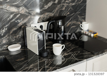 A Stylish Modern Kitchen Counter Featuring Sleek Coffee Machines and Elegant Cups 131328397