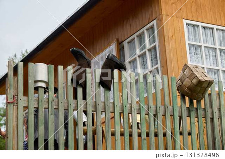 Charming and artistic unique fence details featuring colorful boots and a basket near a wooden house 131328496