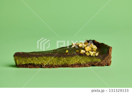 Savor the Delicious Matcha Chocolate Tart Slice against a Vibrant Green Background Savor the Delicious Matcha Chocolate Tart Slice against a Vibrant Green Background 131329133