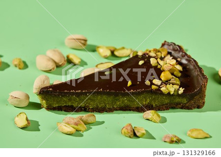 Decadent Chocolate Pistachio Tart Slice Beautifully Presented on a Green Background 131329166