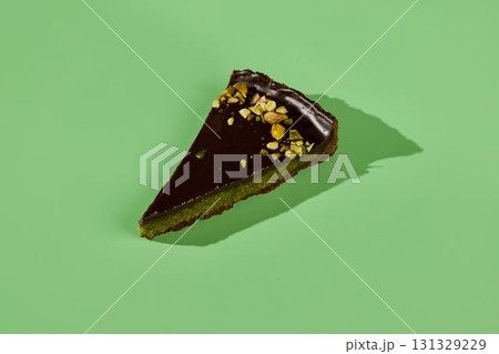 Indulgent and Decadent Slice of Chocolate Cake Decorated with Pistachio on a Green Backdrop 131329229