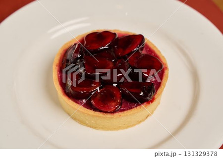 A Delicious Cherry Tart with a Glossy Glaze Artistically Presented on a Pristine White Plate 131329378