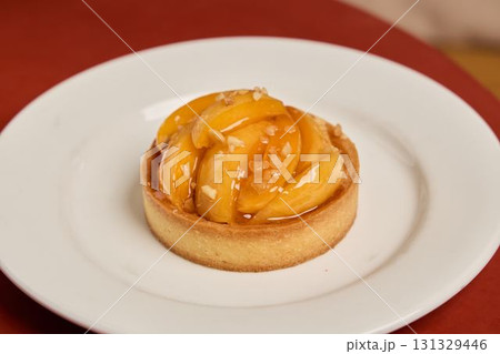 Indulge in a Delicious Peach Tart adorned with Glaze presented on an Elegant White Plate 131329446