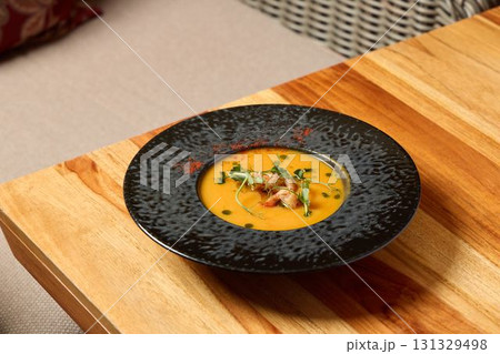 Indulge in a Delicious, Creamy Soup That Is Beautifully Served in an Elegant Black Bowl Indulge in a Delicious, Creamy Soup That Is Beautifully Served in an Elegant Black Bowl 131329498